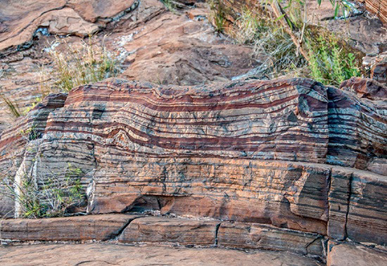This image displays the distinct stripes of iron-rich and silica-rich rocks, known as Banded Iron Formations, located at Fortescue Falls in Karijini National Park, Western Australia.
