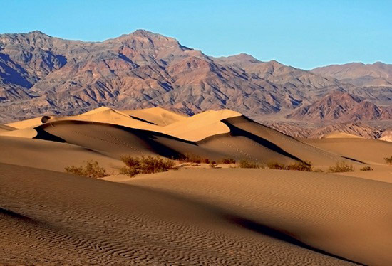 Sand dunes and dry mountains in Death Valley National Park, showcasing the valley's unique geological and climatic features