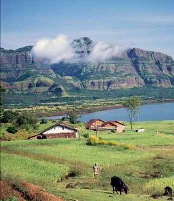 A scenic pastoral landscape in the Western Ghats Mountains of southern India, showcasing the layered volcanic hills of the Deccan Traps