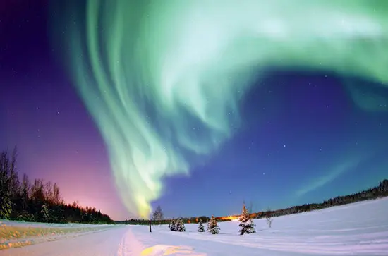 The aurora borealis, or northern lights, gleaming brightly over Bear Lake, Alaska, in January 2005. Auroral displays like this are the result of high-energy solar-wind particles interacting with Earth's magnetic field and with particles trapped in the Van Allen radiation belts.