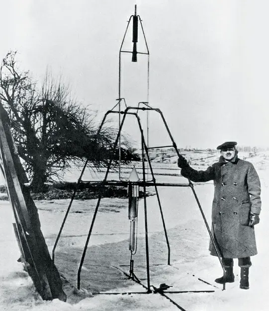 Robert Goddard posing with his first liquid-fueled rocket, launched from Auburn, Massachusetts, on March 16, 1926. This rocket had a combustion chamber and nozzle different from modern rockets.