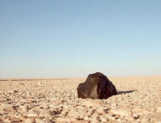 A 14-ounce (408-gram) ordinary chondrite meteorite discovered in 2008 on the rocky terrain of the Rub 'al-Khali desert near Ash-Sharqı¯yah, Saudi Arabia. The black exterior is a thin fusion crust created as the rock rapidly passed through Earth's atmosphere.