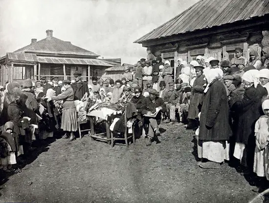A pre-1921 photograph showing Quaker aid workers from England and the US distributing clothing and food to hungry children in the village of Novosemejkino in the Volga River basin near the city of Samara.