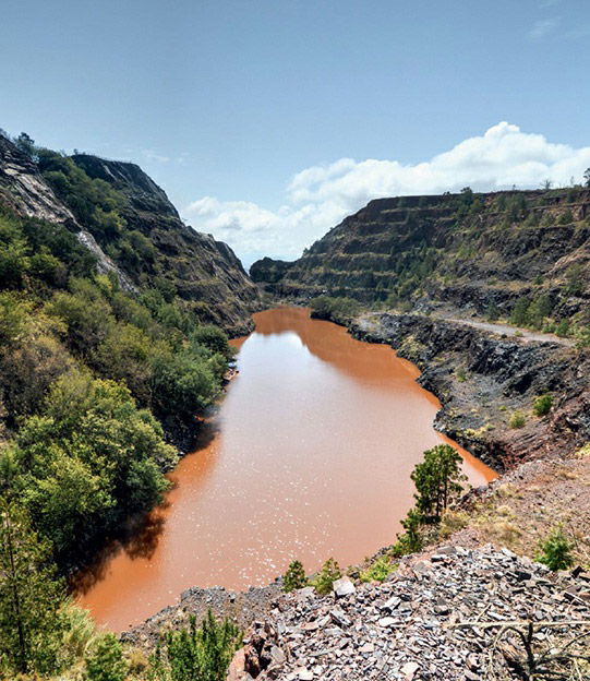 A small pond and stepped cliffs indicate the Ngwenya Mine's location in the Kingdom of Swaziland, one of the earliest known iron